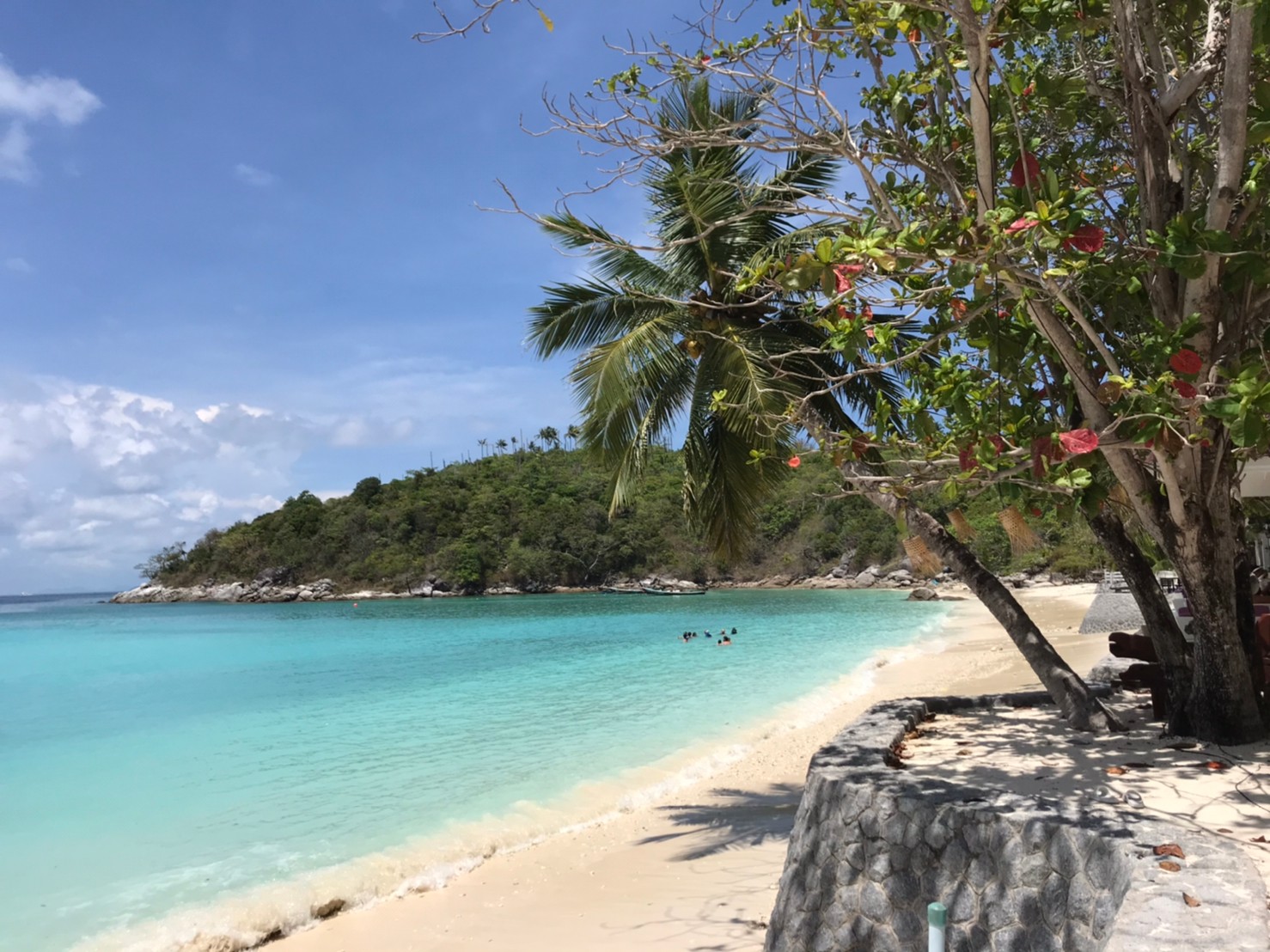 Palm-fringed bay with snorkellers on a 5 Star Marine island stop