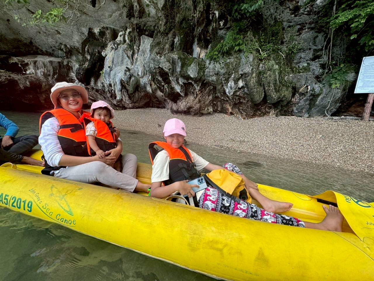 Family relaxing in a John Gray's Sea Canoe kayak beside a cave beach