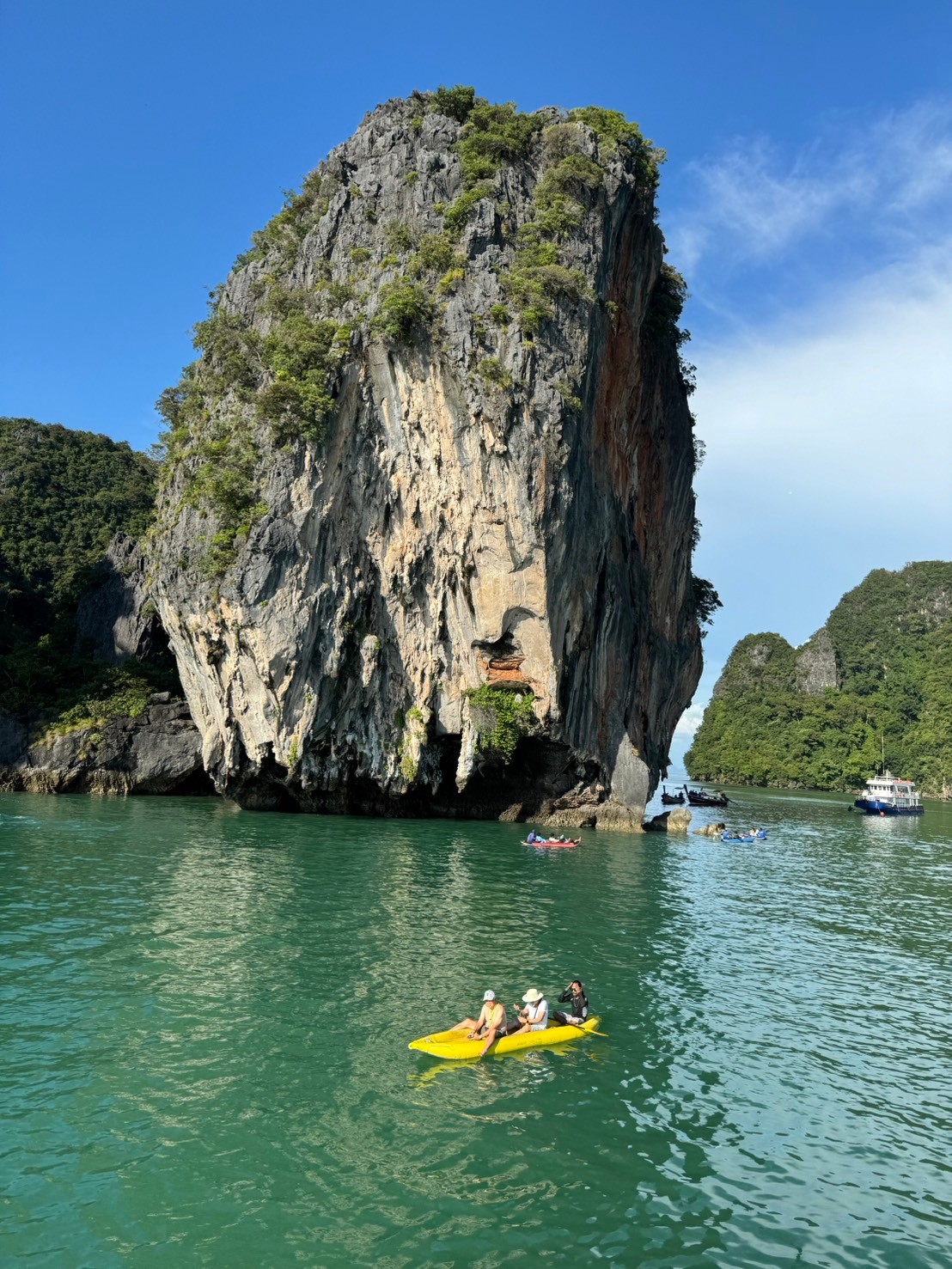 Yellow sea kayak beneath a towering limestone karst in Phang Nga Bay